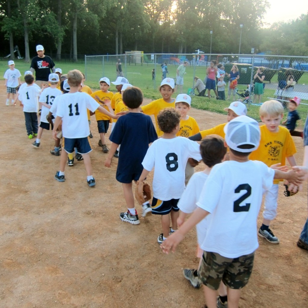 HMB's two T-ball teams, the White Tigers and the Gold Tigers, congratulate each other after a game as Gold coach Michael Adams looks on. Photo by Catie Currie.