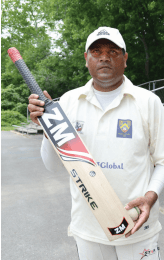 Waqas Shahid, who has competed at the national level, shows off his cricket bat. Shahid plays for the Virginia Cricket Club, shown here warming up on the field. Photo by Megan J. Brockett.