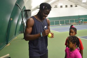 Frances Tiafoe signing a ball in College Park at the JTCC
